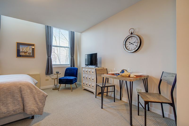 Cozy living space with modern decor, featuring a blue chair, TV, and dining area.