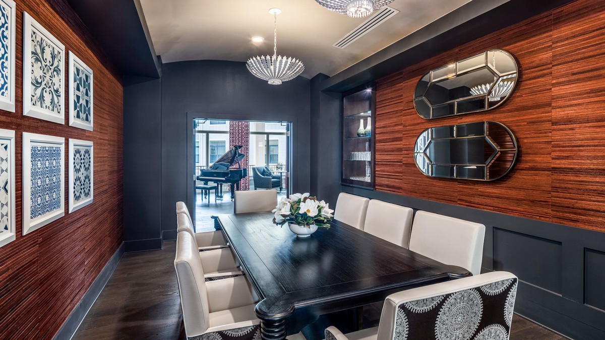 A modern, luxurious dining room featuring a long table with white chairs and elegant lighting.
