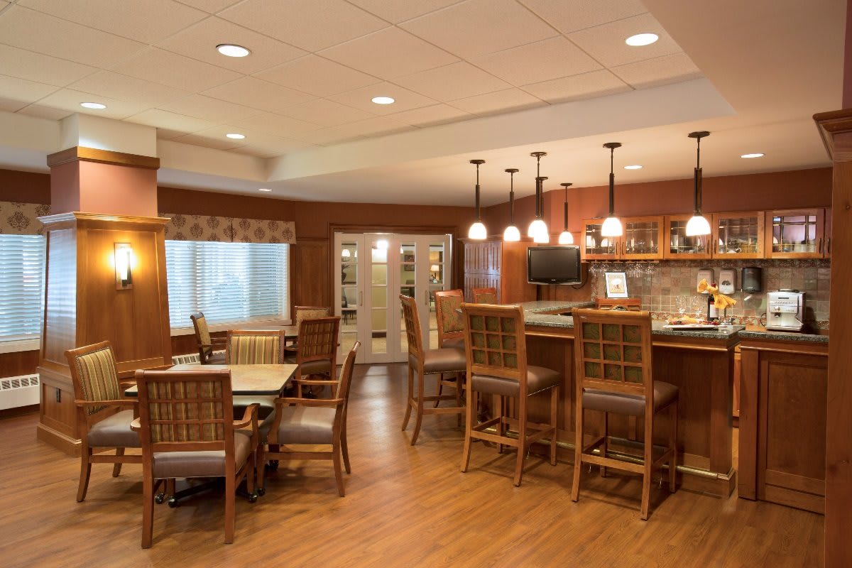A cozy dining area with wooden furniture and a bar counter, featuring warm lighting.