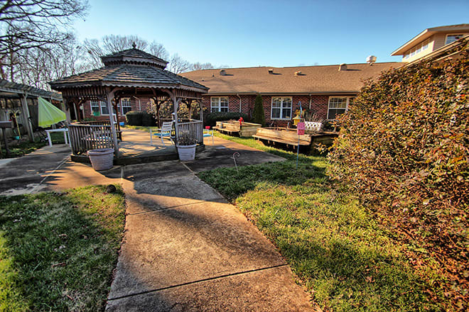 A peaceful garden with a gazebo and pathway leading to a building.