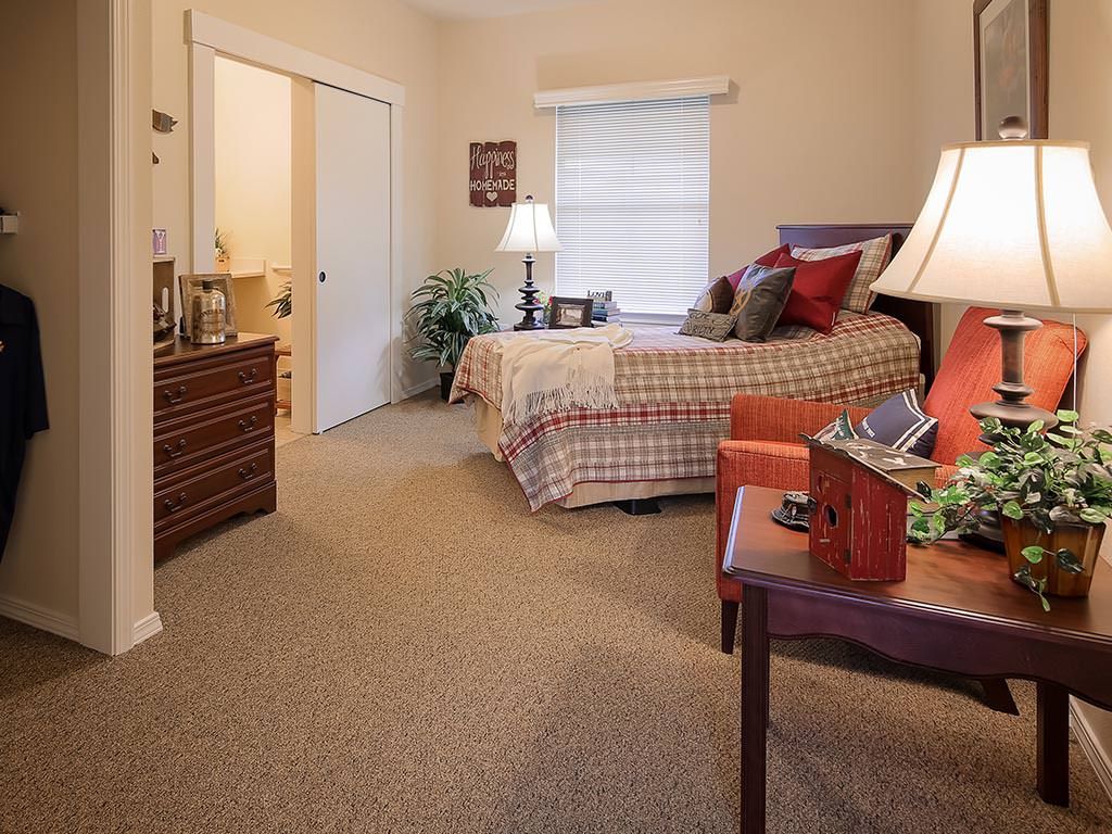A cozy bedroom with a neatly made bed, warm lighting, and comfortable furniture.