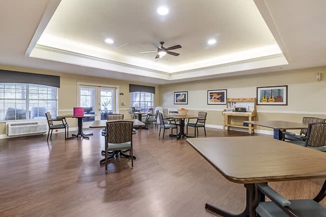 A spacious community dining area with tables and chairs, decorated with wall art and well-lit ceiling lights.