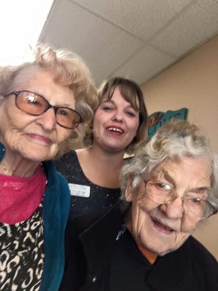 Three women smiling together indoors.