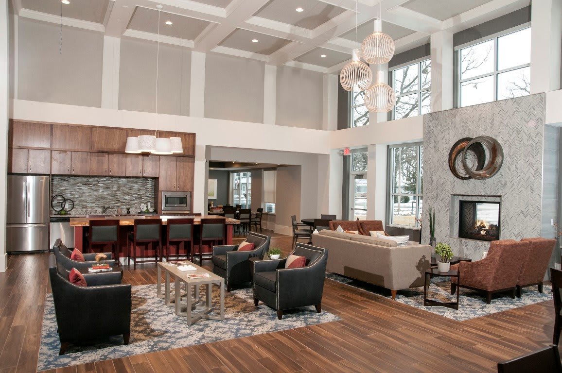 A spacious and modern open-concept living room with a view into the kitchen, featuring luxurious furniture and high ceilings.