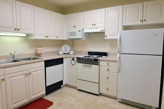 A modern kitchen with white cabinets and standard appliances.