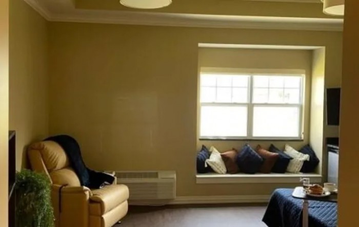A cozy living room with a sofa and a window seat filled with cushions.