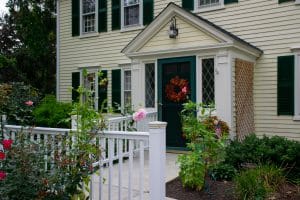 A charming house with a front porch and decorative wreath on the door, surrounded by lush greenery.