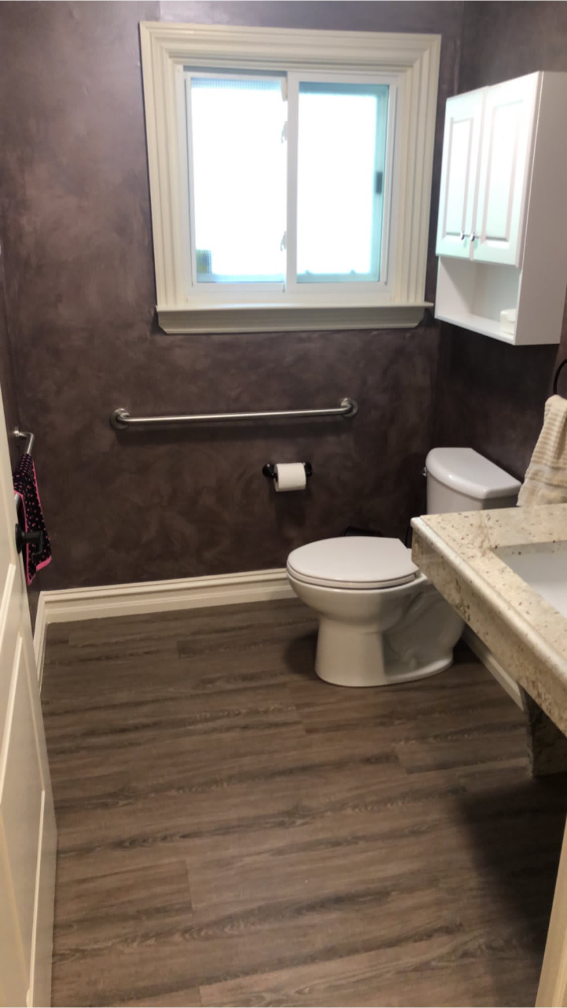 A clean bathroom with a toilet, sink, and window.