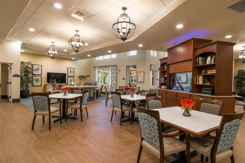 A cozy dining area with several tables and chairs, adorned with elegant lighting fixtures and decorative elements.
