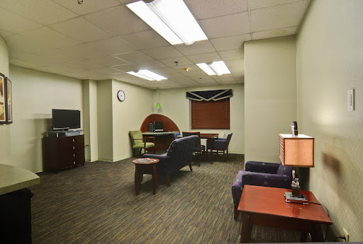 A modern office interior featuring a waiting area with couches and a desk.