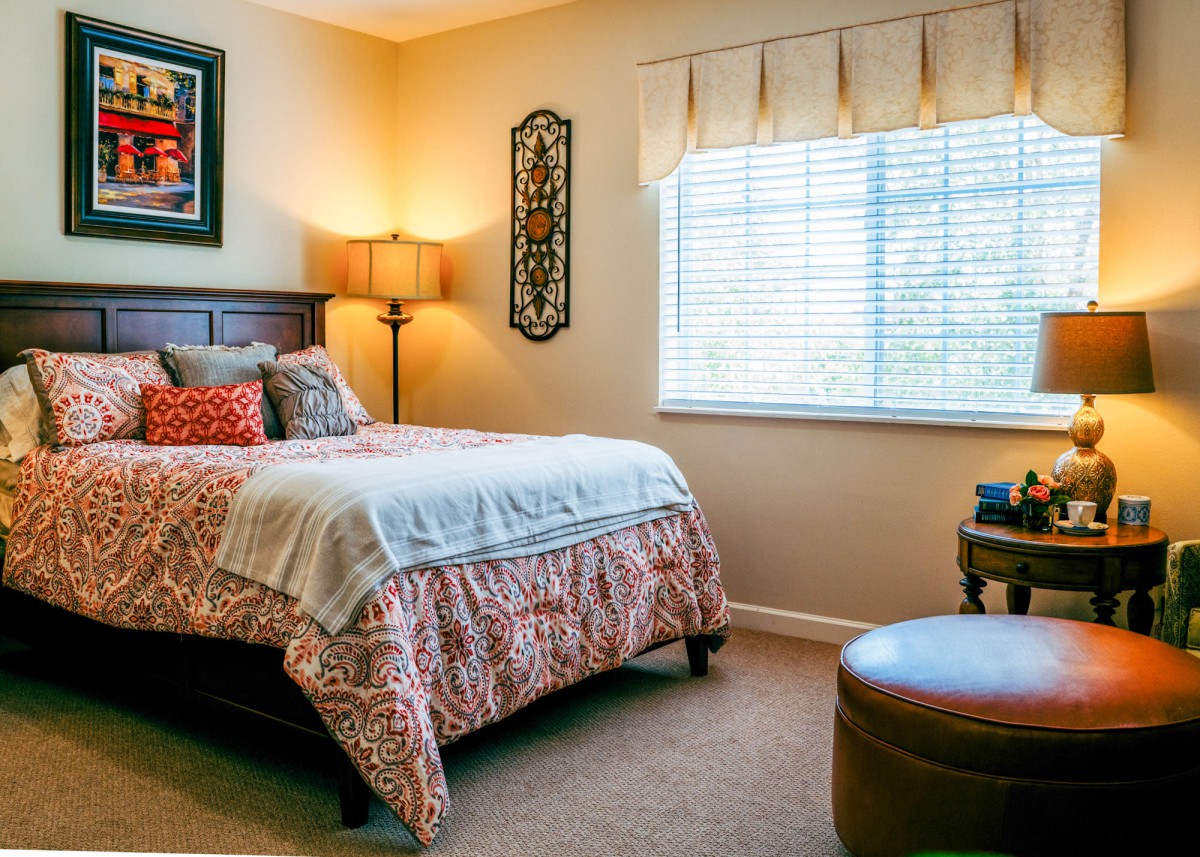 A cozy bedroom with a neatly made bed, warm lamp, and stylish decor.