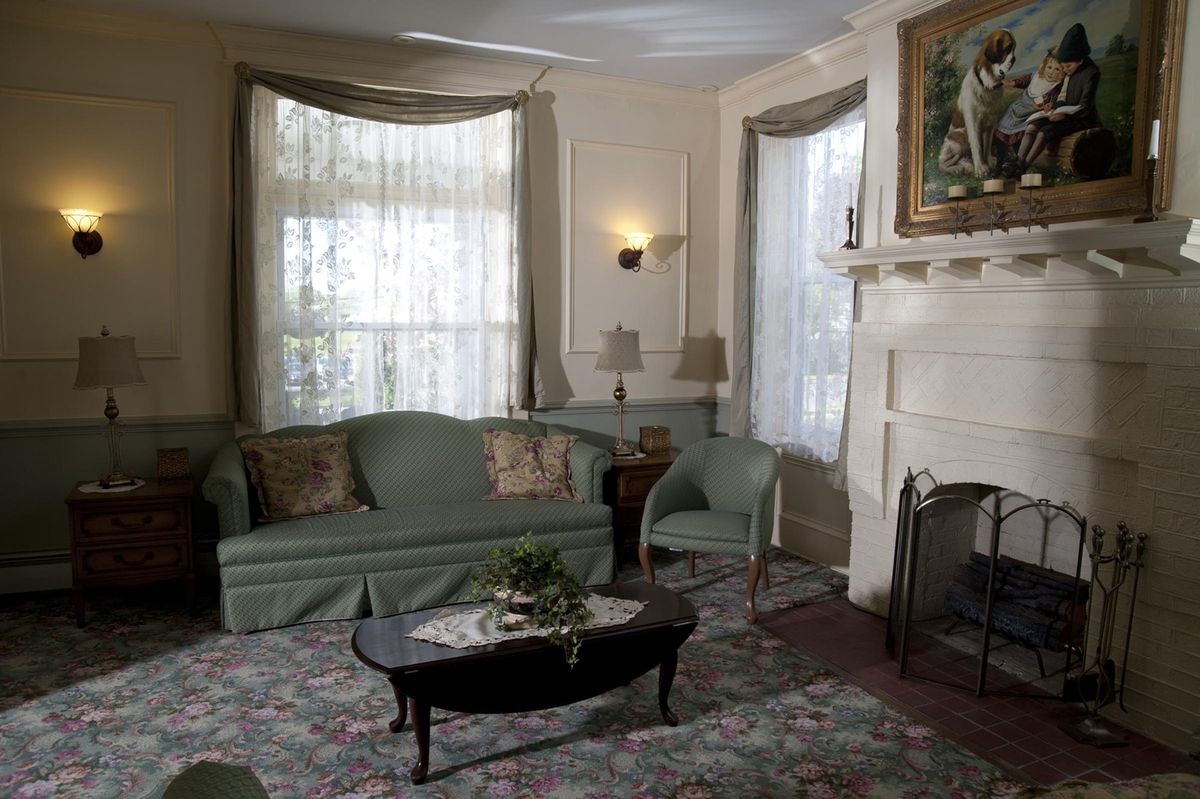 A traditional living room with a green sofa, coffee table, and fireplace.