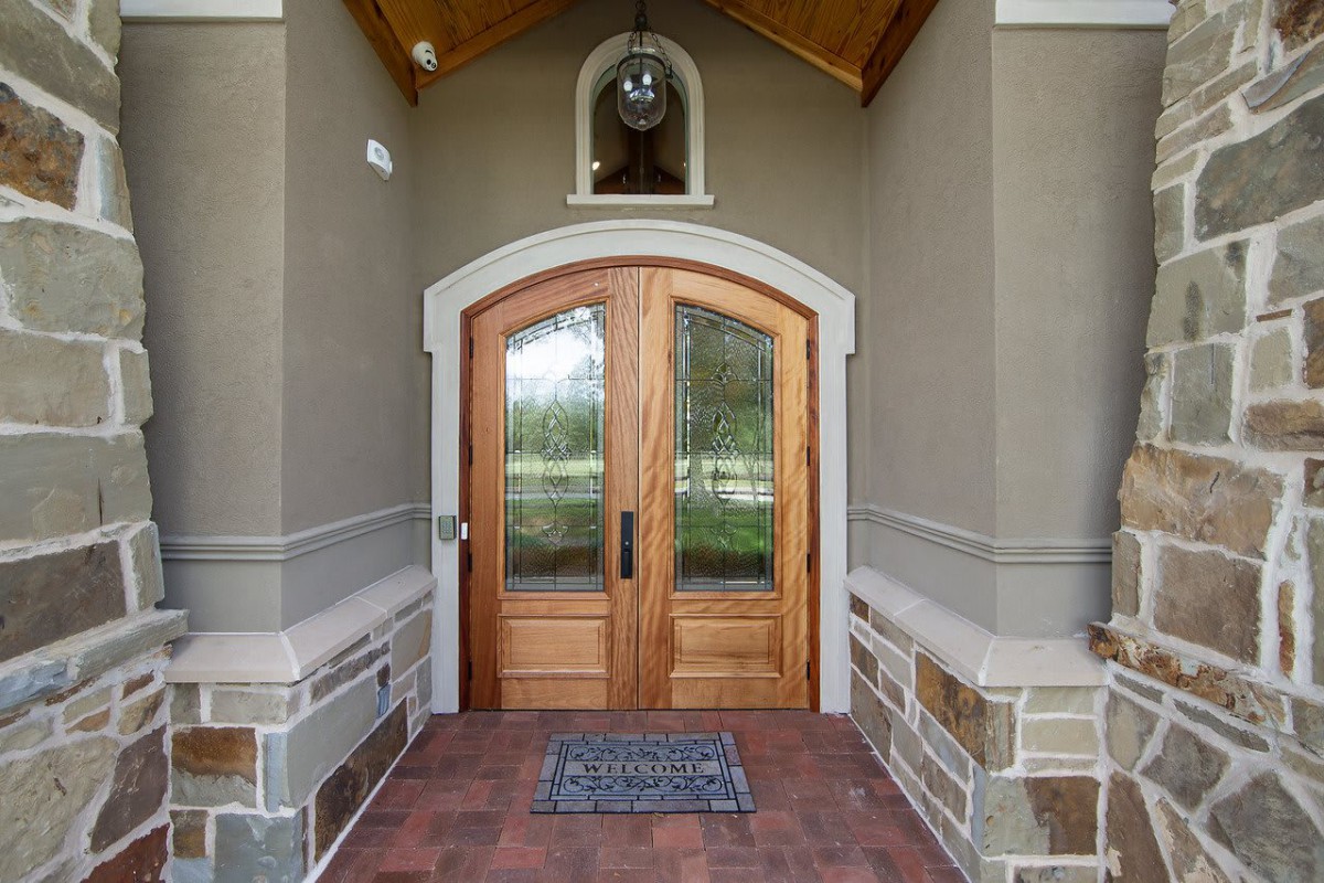 A stylish home entrance with a wooden arched front door and stone accents.