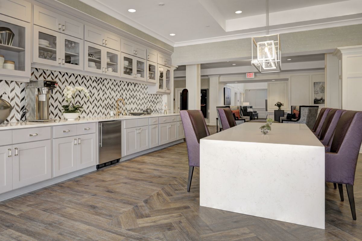 A modern kitchen with white cabinetry, a large island, and herringbone flooring.