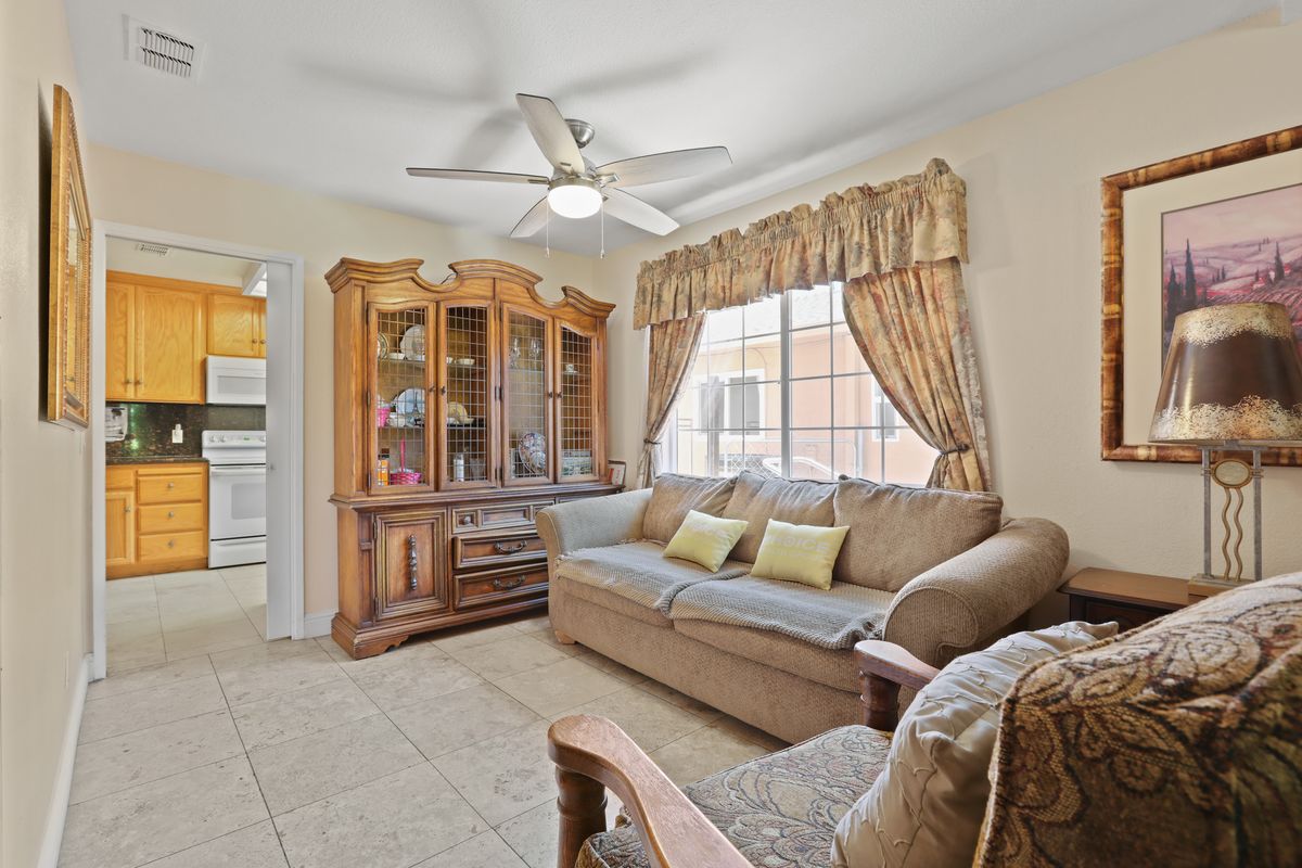 A cozy living room with a comfortable sofa, a wooden cabinet, and large windows with curtains.