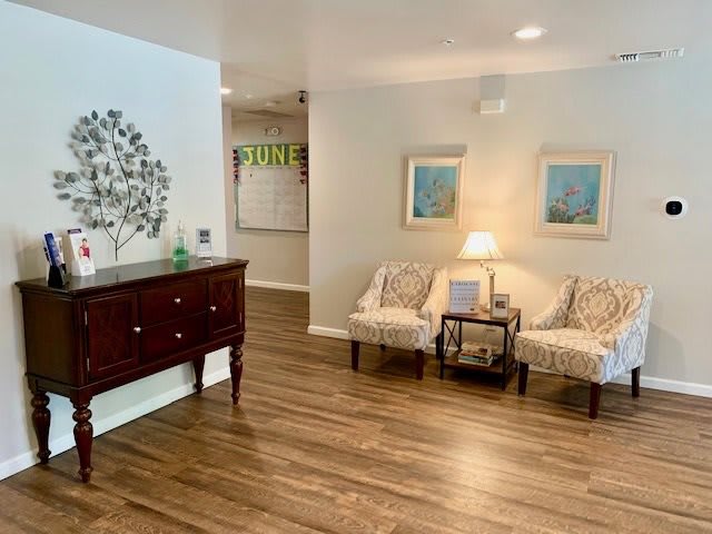 A cozy living room with wood flooring, comfortable seating, and decorative artwork.