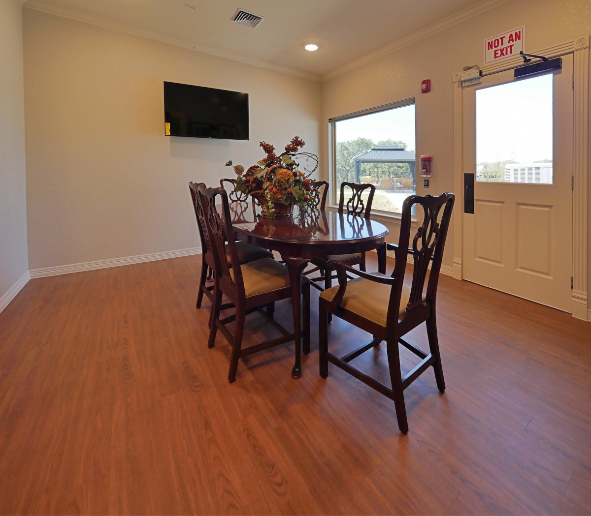 A cozy dining room with a wooden table, chairs, and a wall-mounted television.