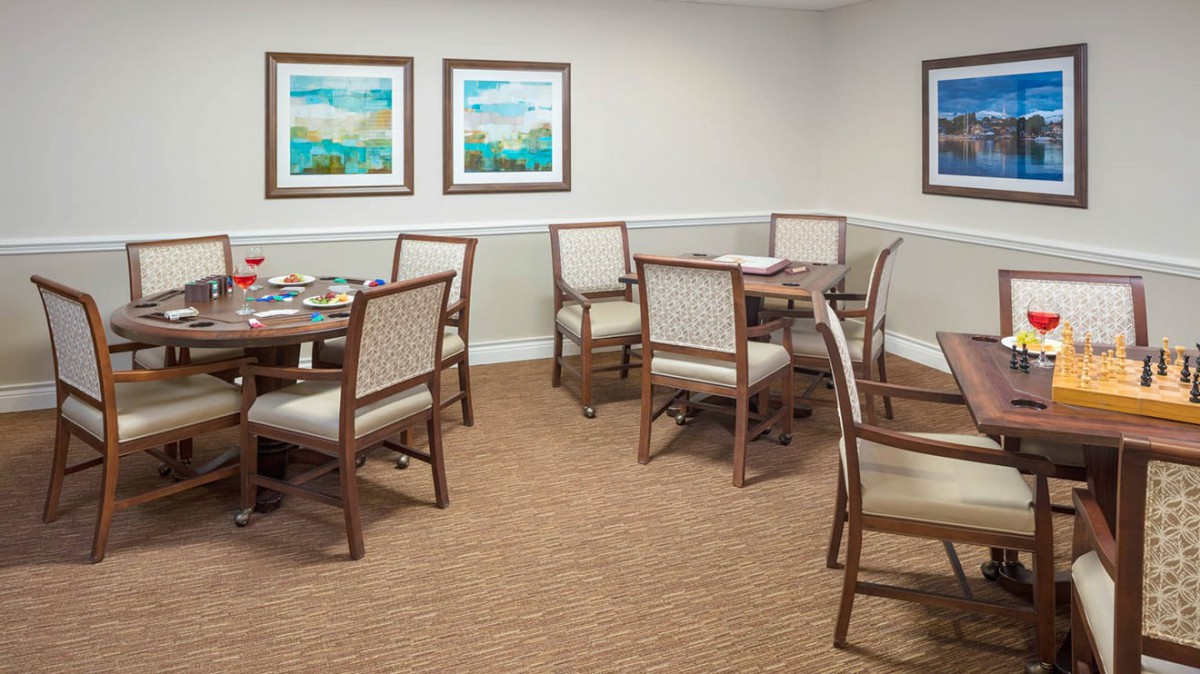 A neatly arranged dining room with tables and chairs, featuring artwork on the walls.