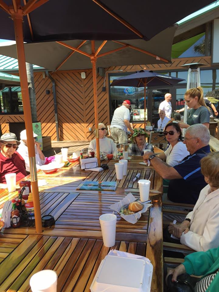 A group of people enjoying a meal together on a sunny patio.