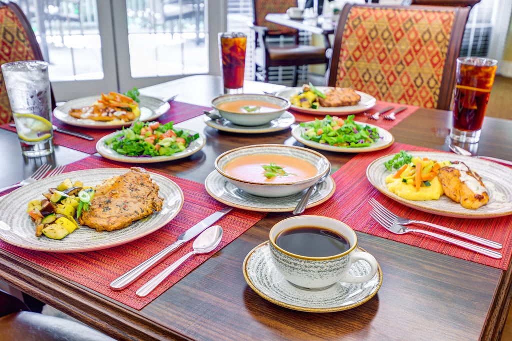 An elegant dining setup with various dishes including salads, soups, and a cup of coffee.