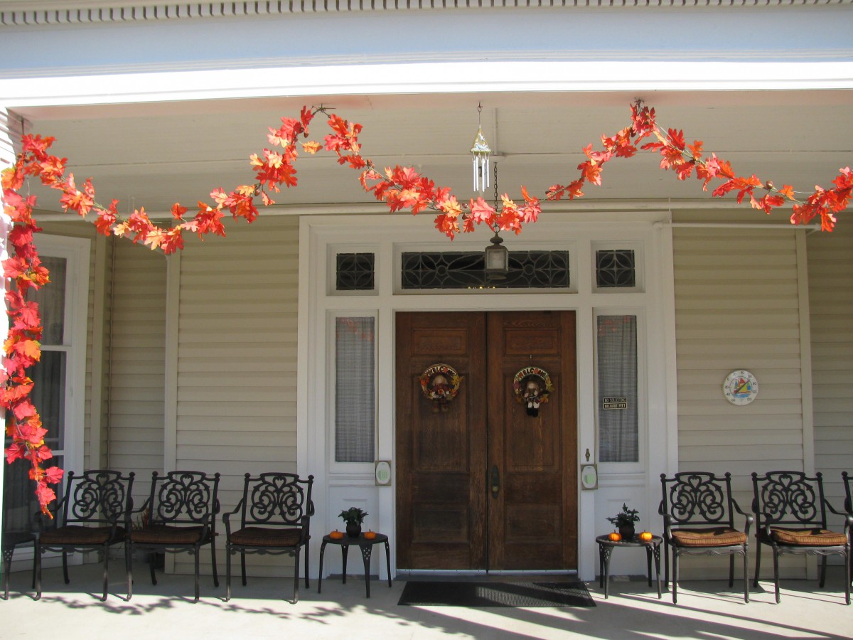 A welcoming porch decorated with autumn-themed garlands above the entrance, featuring several chairs lined up for outdoor seating.