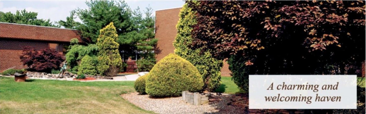 A landscaped garden with neatly trimmed bushes and trees in front of a brick building.
