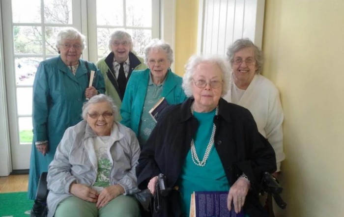 A group of elderly women smiling together indoors.
