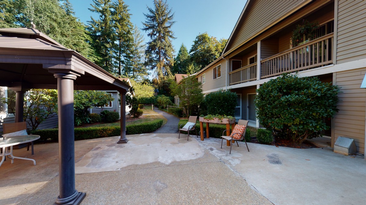 A peaceful outdoor area with chairs and a table surrounded by houses and lush greenery.