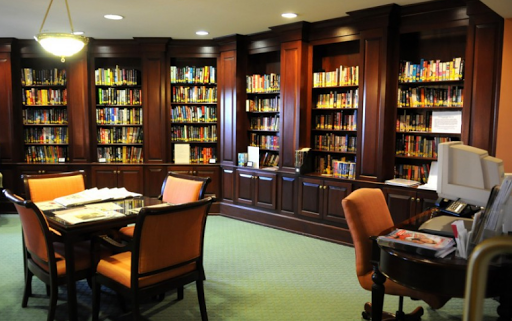 A cozy library space featuring elegant wooden bookshelves filled with books and comfortable seating.