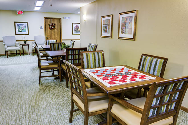 A leisure room with tables and chairs arranged, featuring a checkers board setup.
