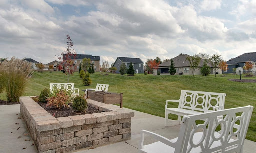 A serene outdoor patio area with seating, overlooking a lush green landscape and residential homes under a cloudy sky.