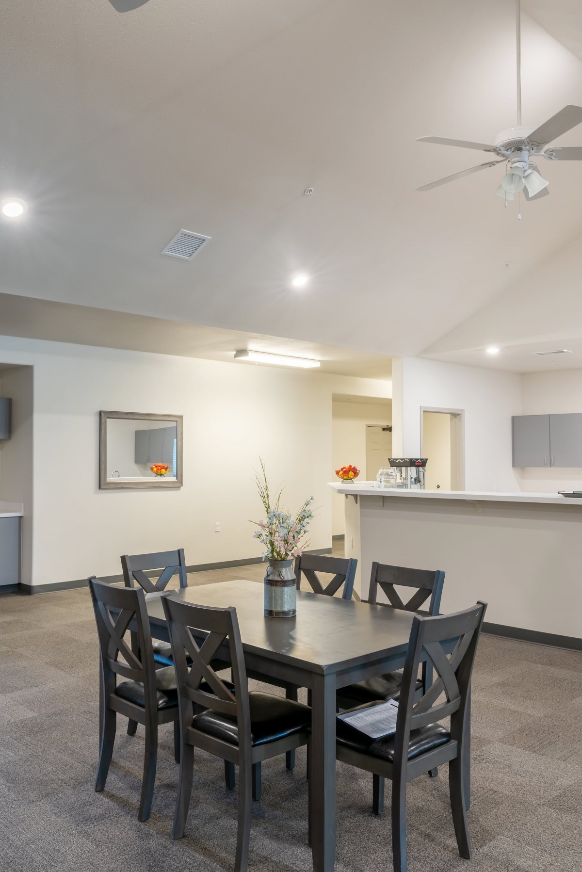 A modern dining room with a wooden table and chairs adjacent to a kitchen bar.