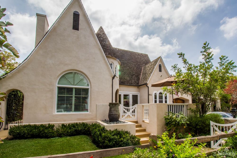 Charming cottage-style house with well-maintained garden and lush greenery.