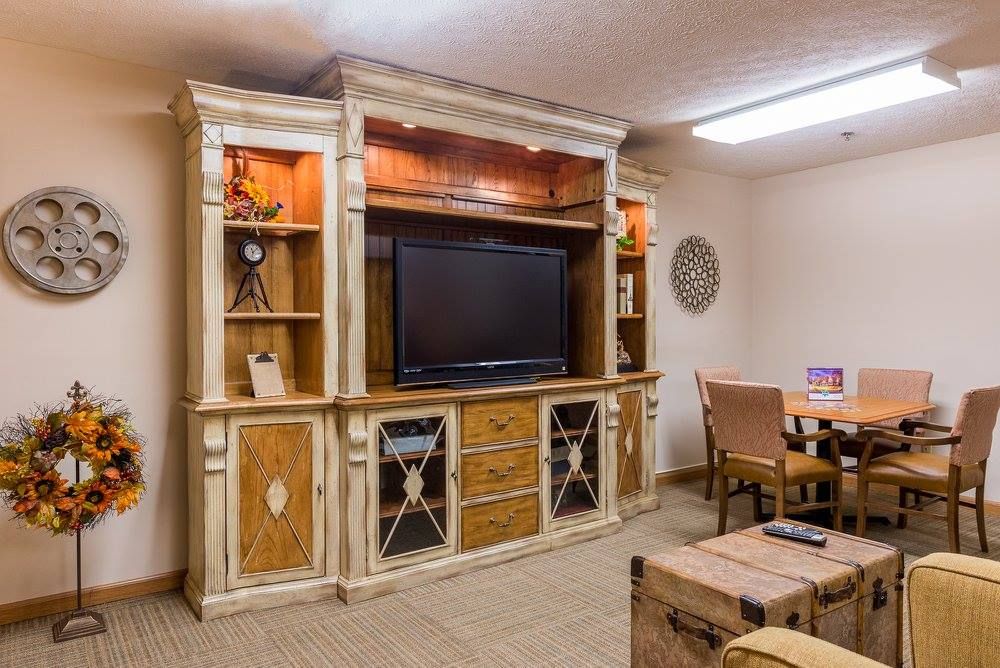 A cozy living room with a rustic entertainment center featuring shelves and a large television.
