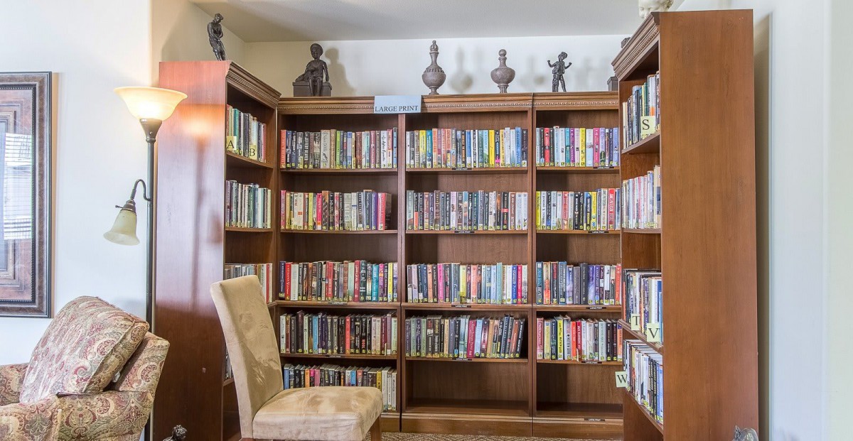 A cozy reading corner featuring a large wooden bookshelf filled with a variety of books and decorative items.