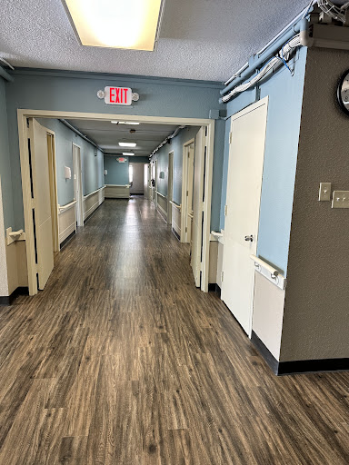 A well-lit corridor featuring multiple doors along the sides and a polished wooden floor.