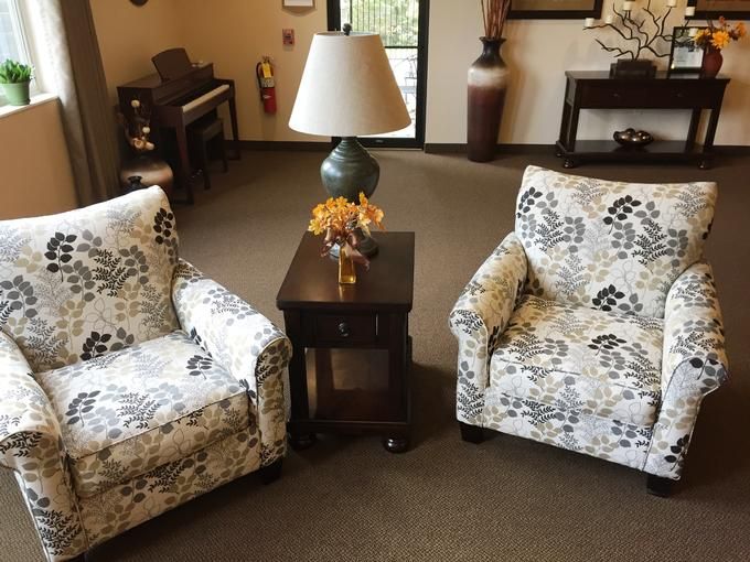 A cozy living room setup with two floral-patterned chairs and a lamp on an end table.