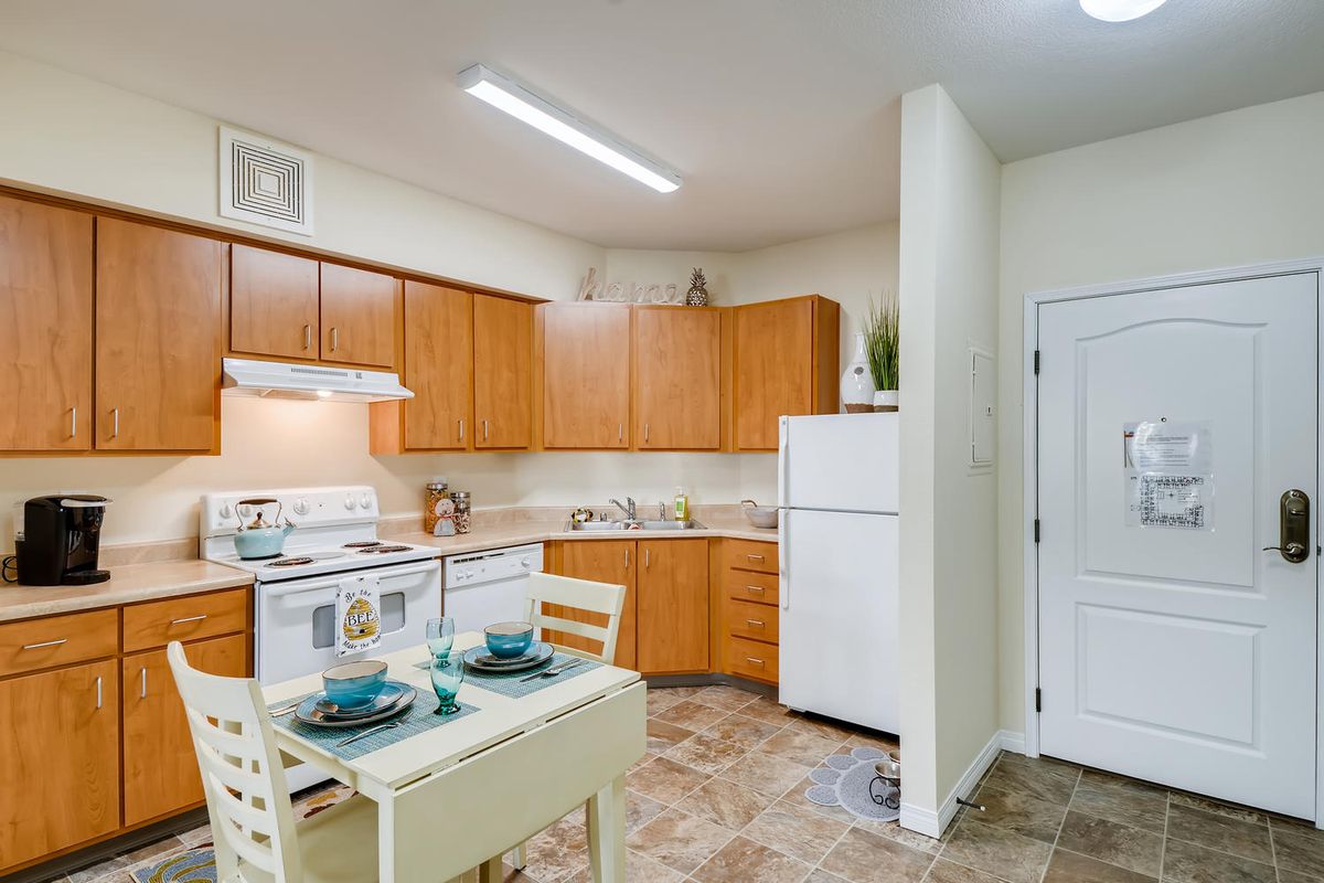 A cozy apartment kitchen with wooden cabinets and a small dining area.