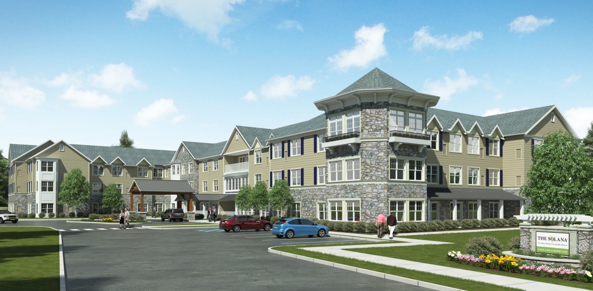 Modern residential building with stone facade and parked cars in front.