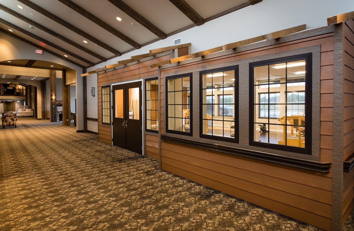 A spacious hallway with wooden beams, large windows, and carpeted flooring.