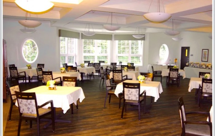 A spacious dining room with neatly arranged tables and chairs, featuring large windows and elegant lighting.