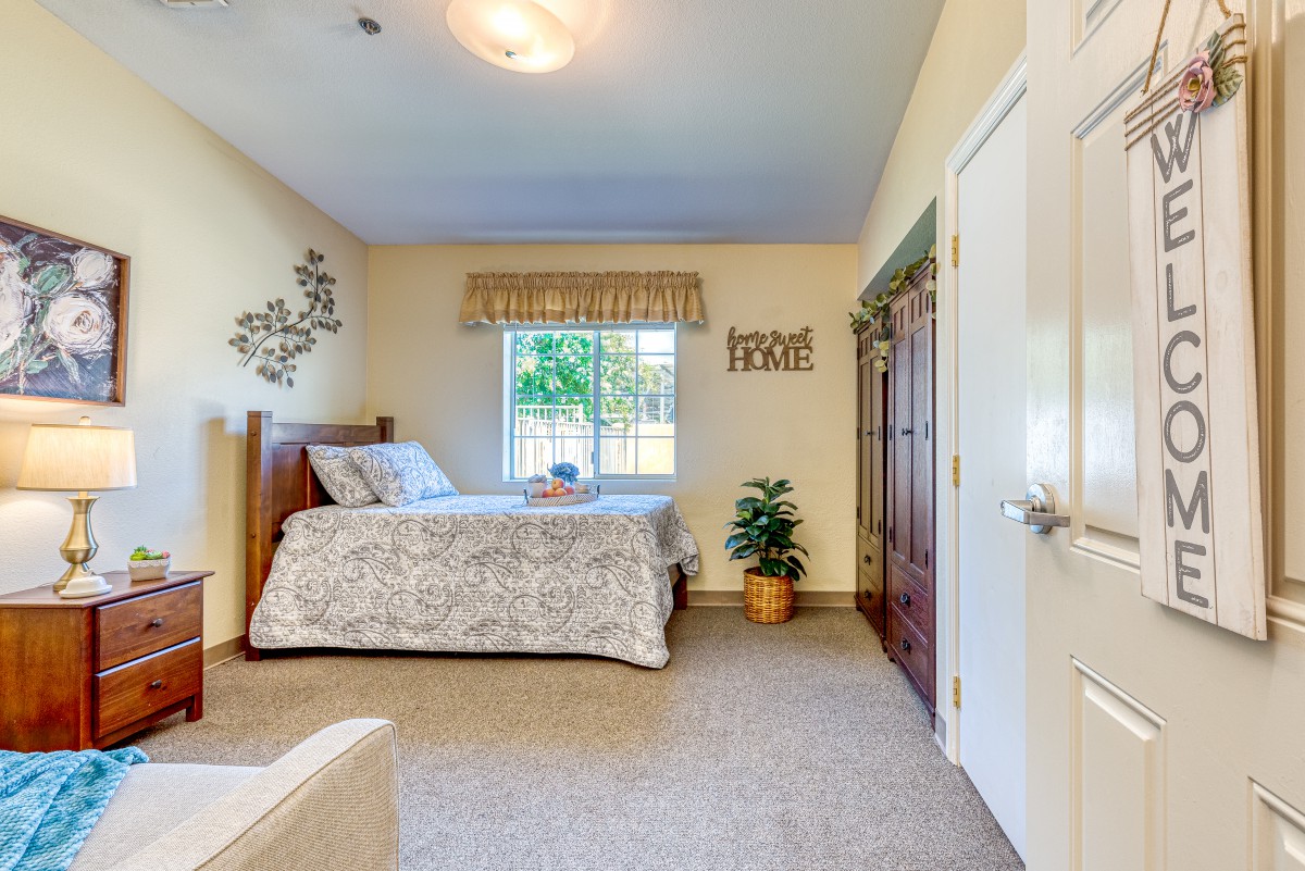 A cozy bedroom with a bed, window, and houseplant.