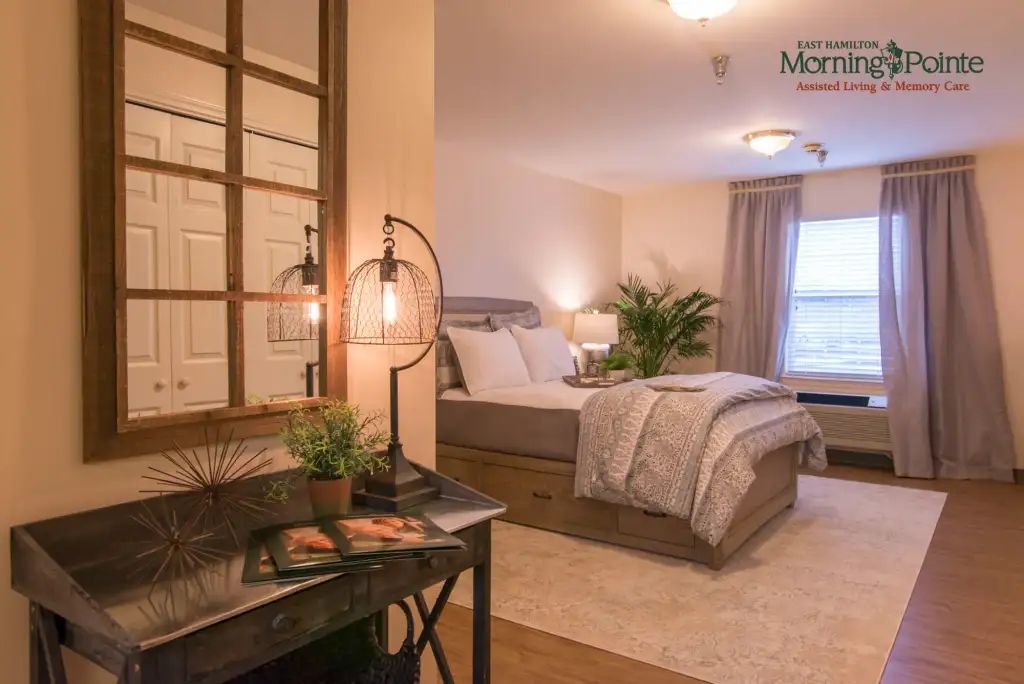 A cozy and modern bedroom with neutral colors, featuring a comfortable bed, stylish lighting, and greenery.