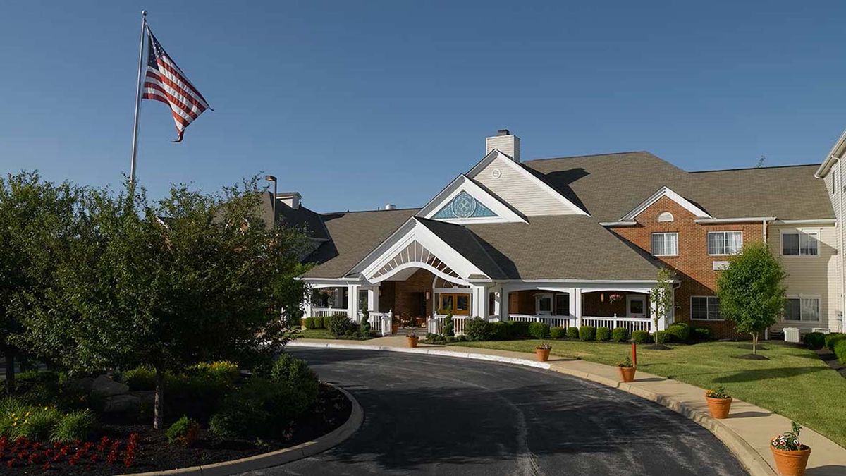 A large residential building with a driveway and flag.