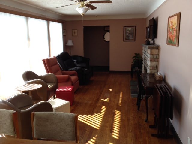 A cozy living room with various seating options, wood flooring, and sunlight streaming through the windows.