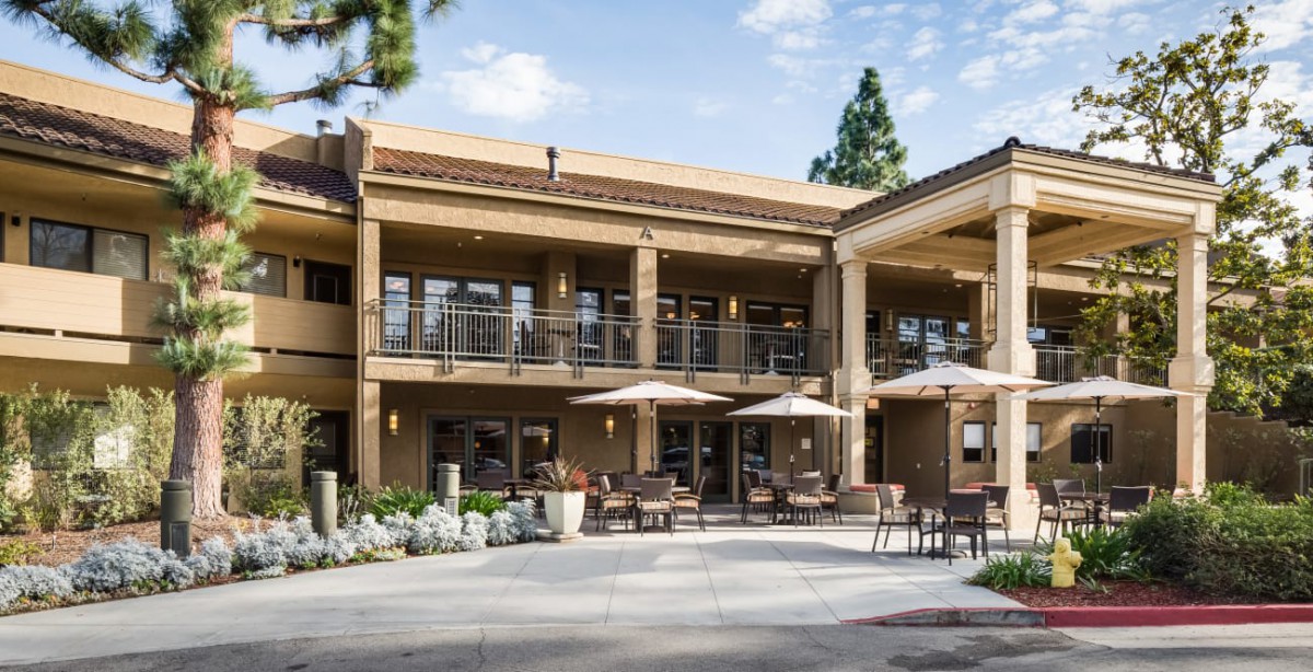 A two-story building with outdoor seating and umbrellas on a sunny day.