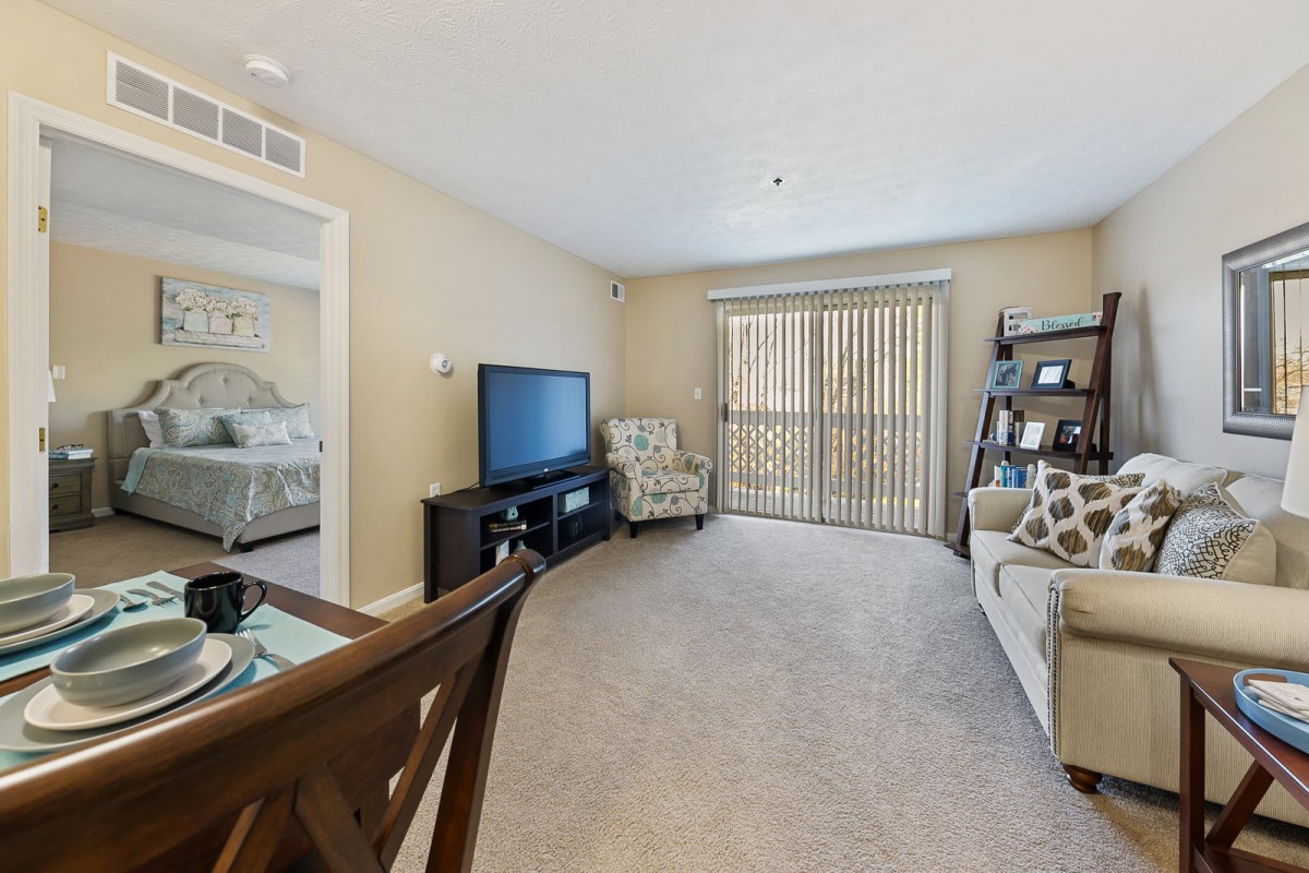 A cozy living room featuring a television, comfortable seating, and a dining area.