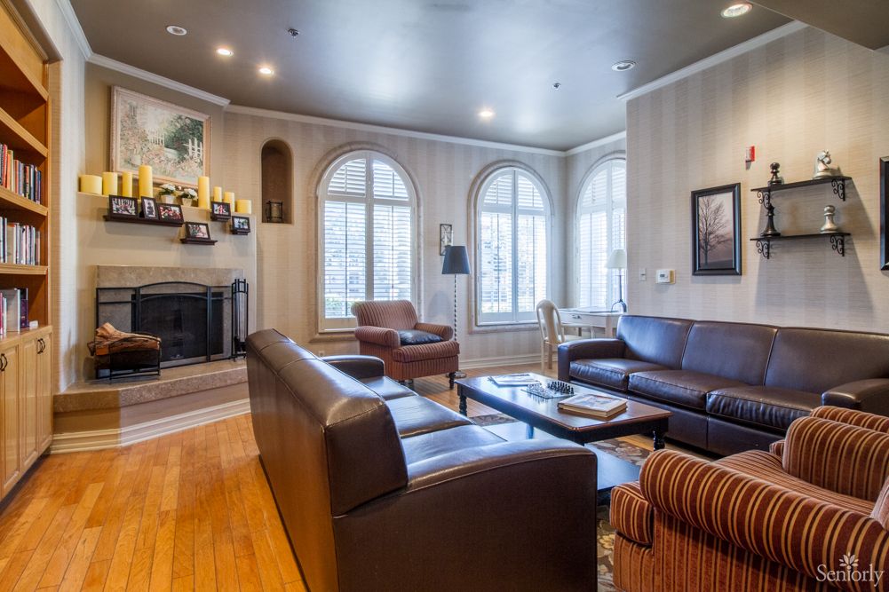 A cozy living room featuring leather sofas, a fireplace, and large arched windows.
