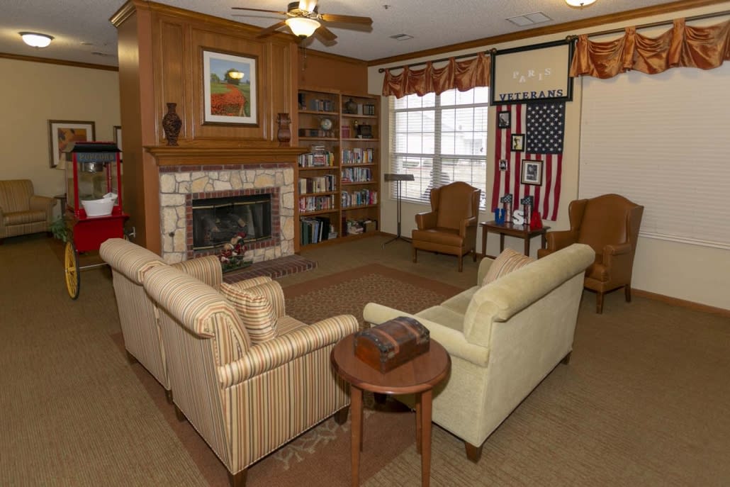 A cozy living room with a fireplace, couches, and a bookshelf.