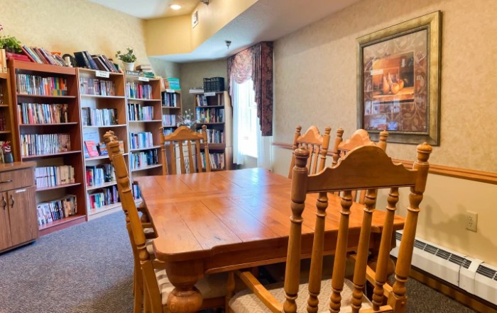 A cozy library room featuring wooden furniture and filled bookshelves.